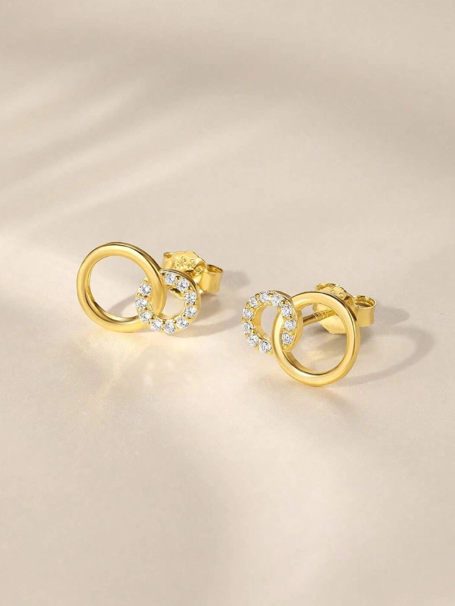 Малки и нежни сребърни обеци проба 925 с позлата. Имат реометричен дизайн - два преплетени кръга, един от които инкрустиран с прозрачни кристали.