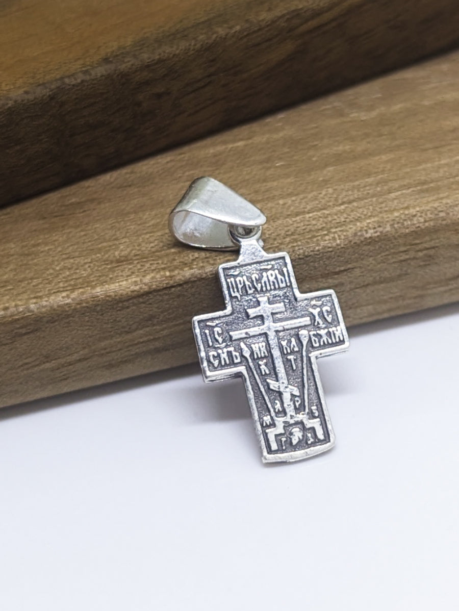 Сребърен православен кръст 925 с релефно изображение на Разпятието Христово (Голгота), ІС ХС и символи – лицева страна на двулицев оксидиран медальон.