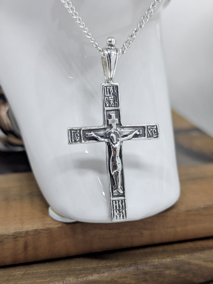 Сребърен православен кръст 925 с високо релефно изображение на Разпятието Христово (ІНЦІ, ІС ХС) – лицева страна на двулицев оксидиран медальон.