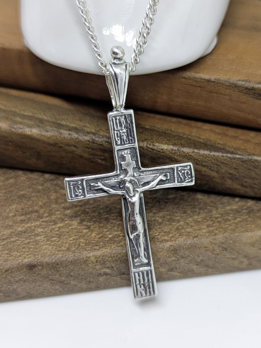 Сребърен православен кръст 925 с високо релефно изображение на Разпятието Христово (ІНЦІ, ІС ХС) – лицева страна на двулицев оксидиран медальон.