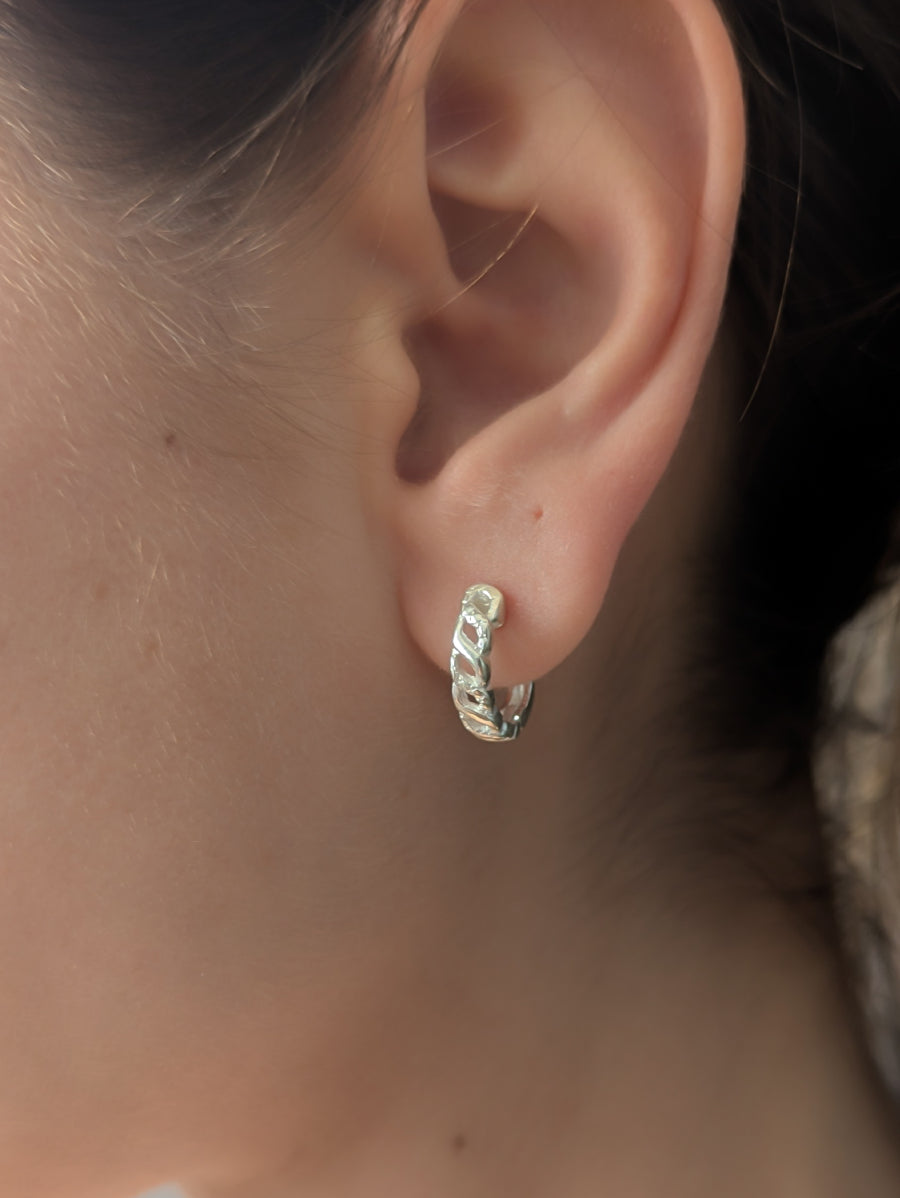 Малки сребърни обеци тип халки (huggie) проба 925 с плътен, изрязан дизайн, имитиращ верига или преплетени звена, носени на ухото